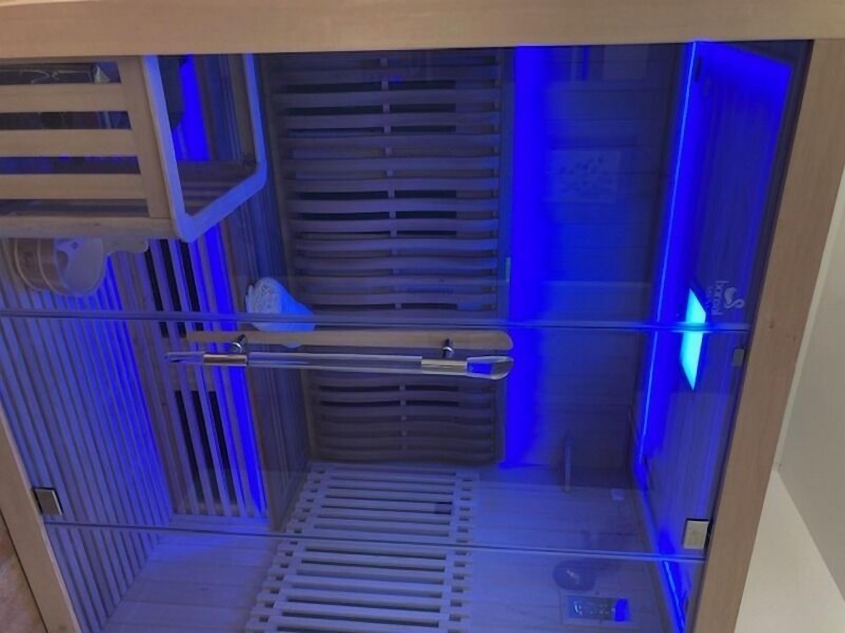 A room with a wooden slatted wall, a metal rack, and a blue-lit corner.