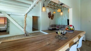 Eine moderne Küche mit Holztischplatte, hängenden Pendelleuchten und einer Essecke mit Tisch für zwei Personen.
