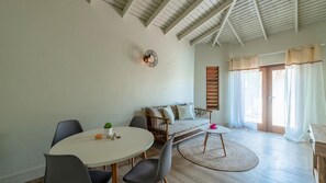 A spacious room with a high ceiling, a round dining table, a sofa, and a large window with curtains. - Hofi Paradise @ Sunset Heights | Private Pool (Sunset Heights)
