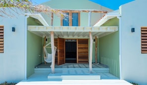 A modern house with a covered porch, a hammock, and a staircase leading to the entrance.