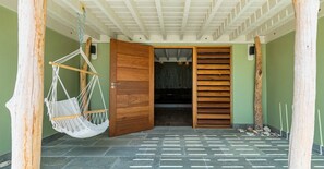 Una habitación con puerta de madera, una silla colgante y piso de baldosas.