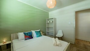 Un dormitorio con cama, almohadas, una lámpara de noche, un armario y una estantería.