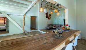 A modern kitchen with a wooden countertop, hanging pendant lights, and a dining area with a white chair. - Hofi Paradise @ Sunset Heights | Private Pool (Sunset Heights)