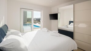 A hotel room with a bed, a TV, a large mirror, and a view of an outdoor swimming pool. - Beach front home in Babici (Babici)
