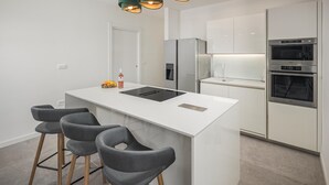 A modern kitchen with a central island, bar stools, a refrigerator, an oven, and a built-in dishwasher. - Beach front home in Babici (Babici)