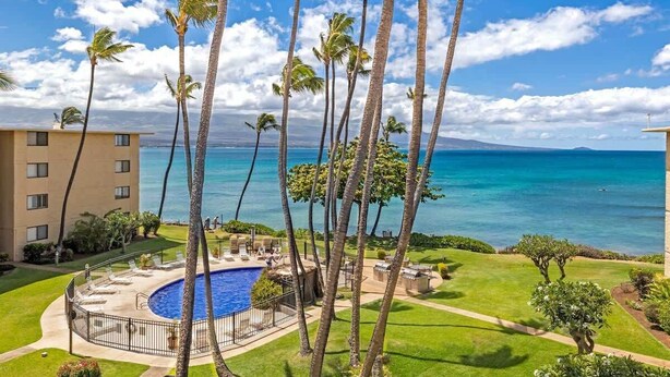 A hotel with a pool, palm trees, and a view of the ocean. - Top Floor Condo- Ocean Views w Pool Steps to Beach (Wailuku)