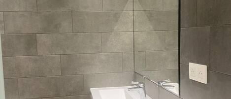 A modern bathroom with a rectangular sink, a mirror, and a toilet.
