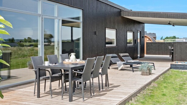 Ein moderner Essbereich im Freien mit Tisch, Stühlen, einem Grill und Blick auf die umliegende Landschaft.