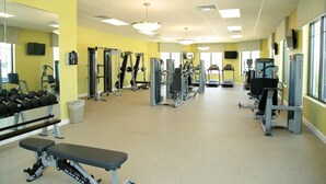 Un gimnasio con equipos de ejercicio variados, espejos y una banca.