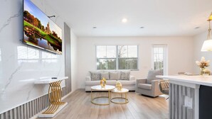 Un salon moderne avec un canapé, deux tables basses et un téléviseur fixé au mur.