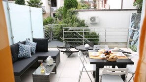 Relax in this stylish outdoor space with a sofa, coffee table, and dining area for two.