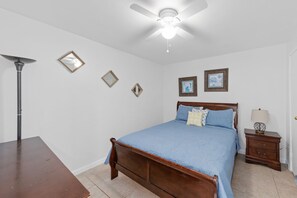 A bedroom with a bed, a nightstand, a lamp, and a ceiling fan.