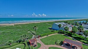 A coastal property with a beach view, a parking area, and a building with a flat roof. - Ocean Views from Aquarius 806! 2 BD 1BA for 4 people (South Padre Island)