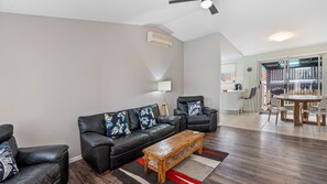 A living room with a sofa set, coffee table, and a dining area with a table and chairs.