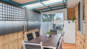 A patio with a table and chairs, a screen, and a refrigerator.