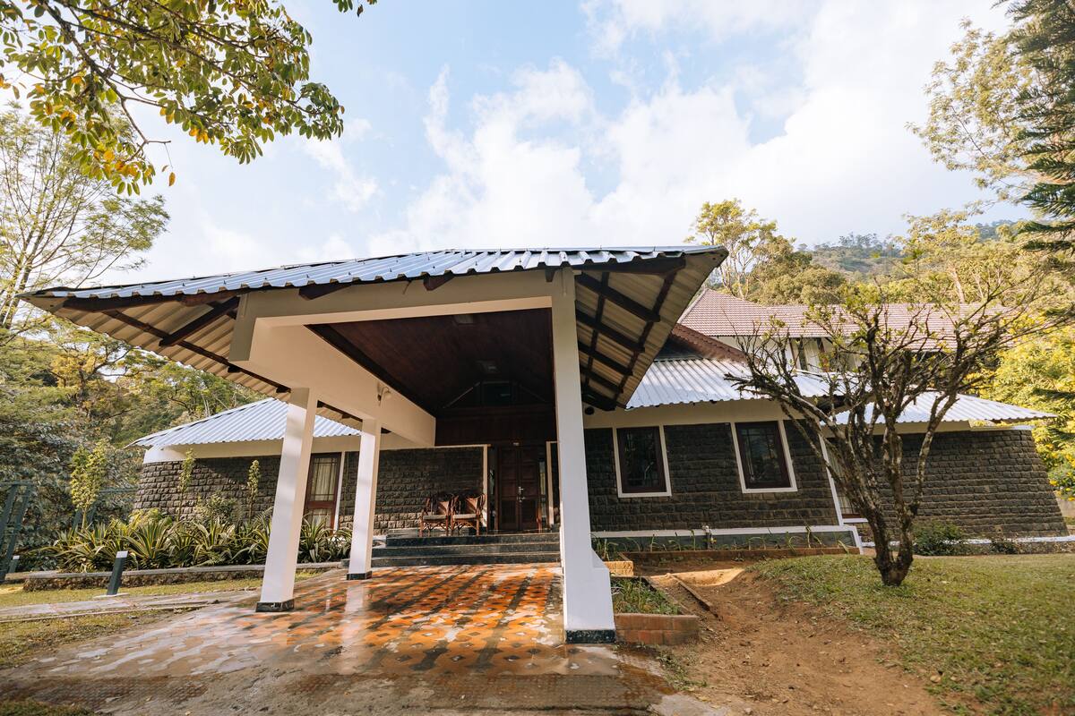 A house with a covered porch, stone walls, and a garden.
