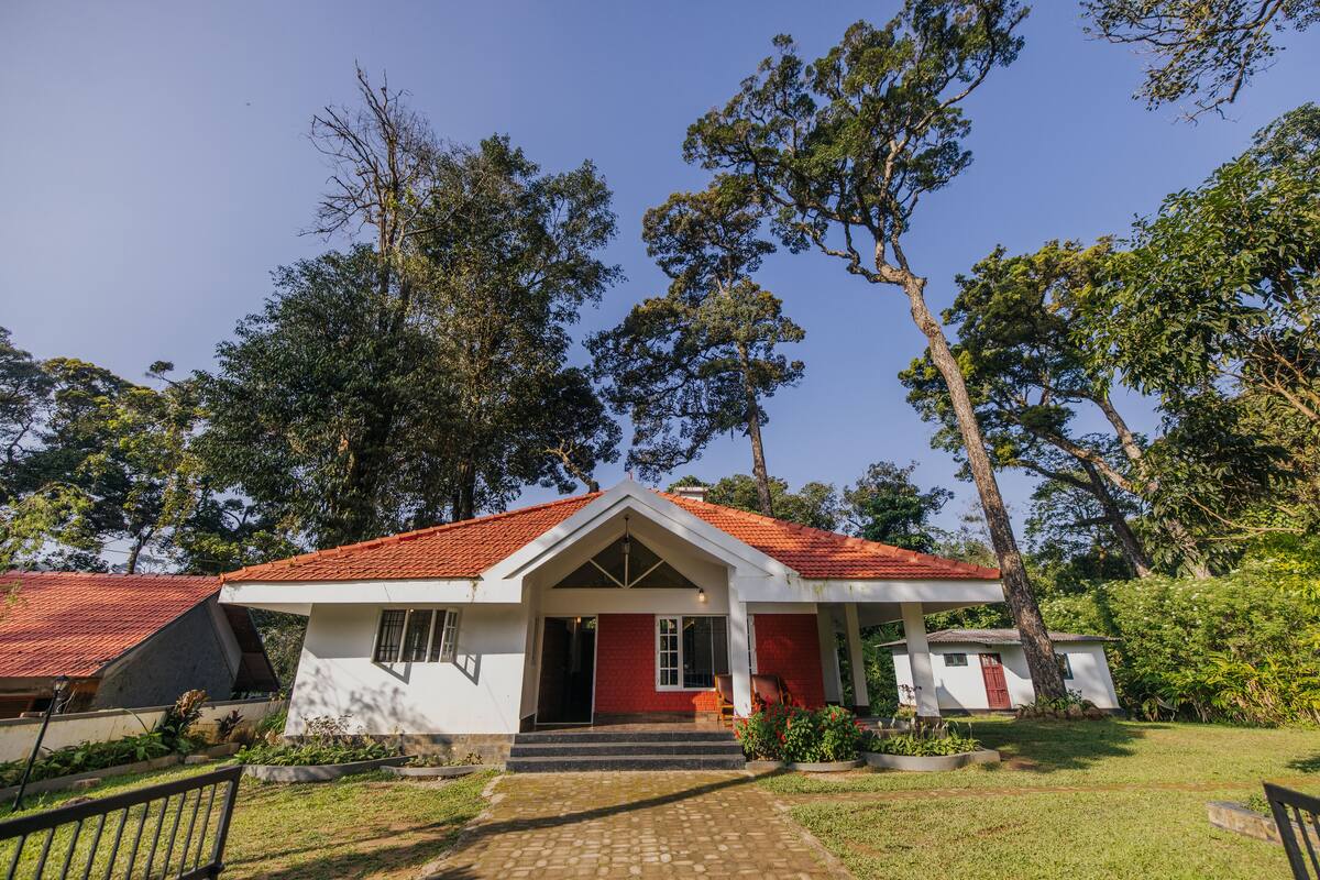 A two-story house with a red-tiled roof, a front porch, and a garden.