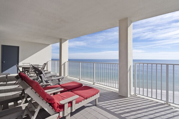 A covered outdoor area with lounge chairs and a view of the ocean. - Windward Pointe 1206 by Liquid Life (Orange Beach)