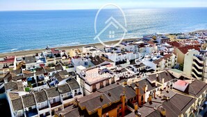 A coastal town with a mix of traditional and modern buildings, a beach in the background, and a clear sky. - 2 bedrooms apartment in front of the sea with stunning views! (Torremolinos)