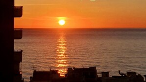 A sunset over a calm sea with buildings silhouetted against the sky. - 2 bedrooms apartment in front of the sea with stunning views! (Torremolinos)