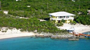 Une propriété située sur la côte, comprenant une grande maison, une plage et un littoral rocheux.