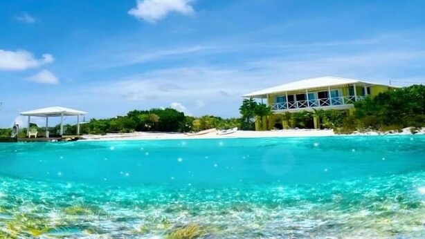 Une propriété située en bord de mer, dotée d’un grand bâtiment, d’une eau turquoise cristalline et d’une végétation luxuriante.