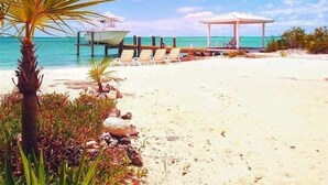 Une plage avec un kiosque, des chaises longues et un quai pour bateaux.