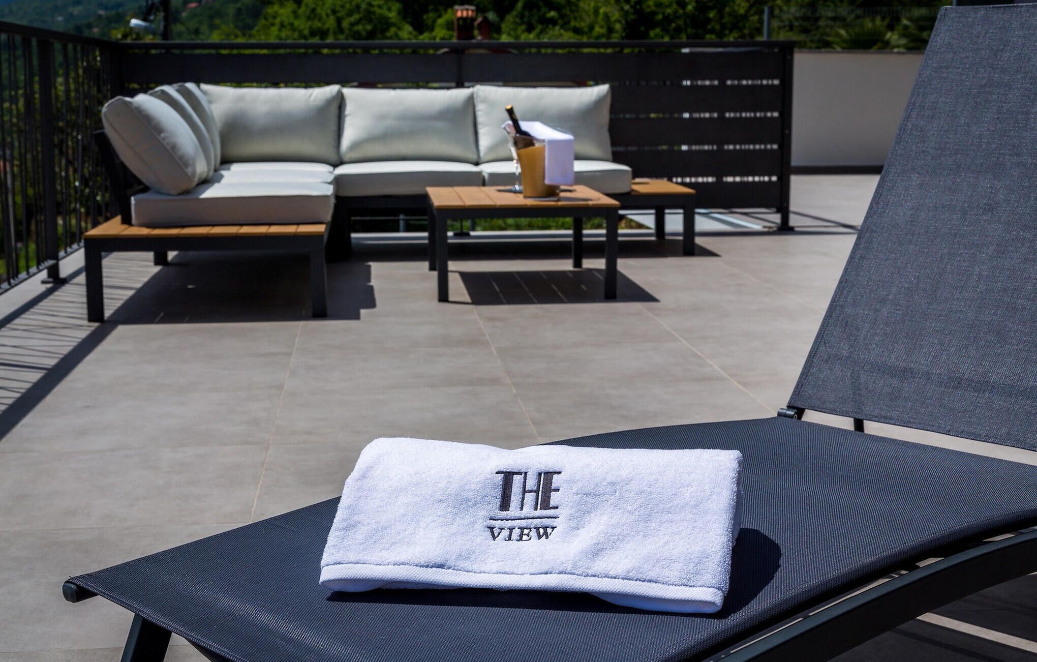 Un fauteuil de relaxation avec une serviette sur laquelle est inscrit « THE VIEW », sur un balcon.