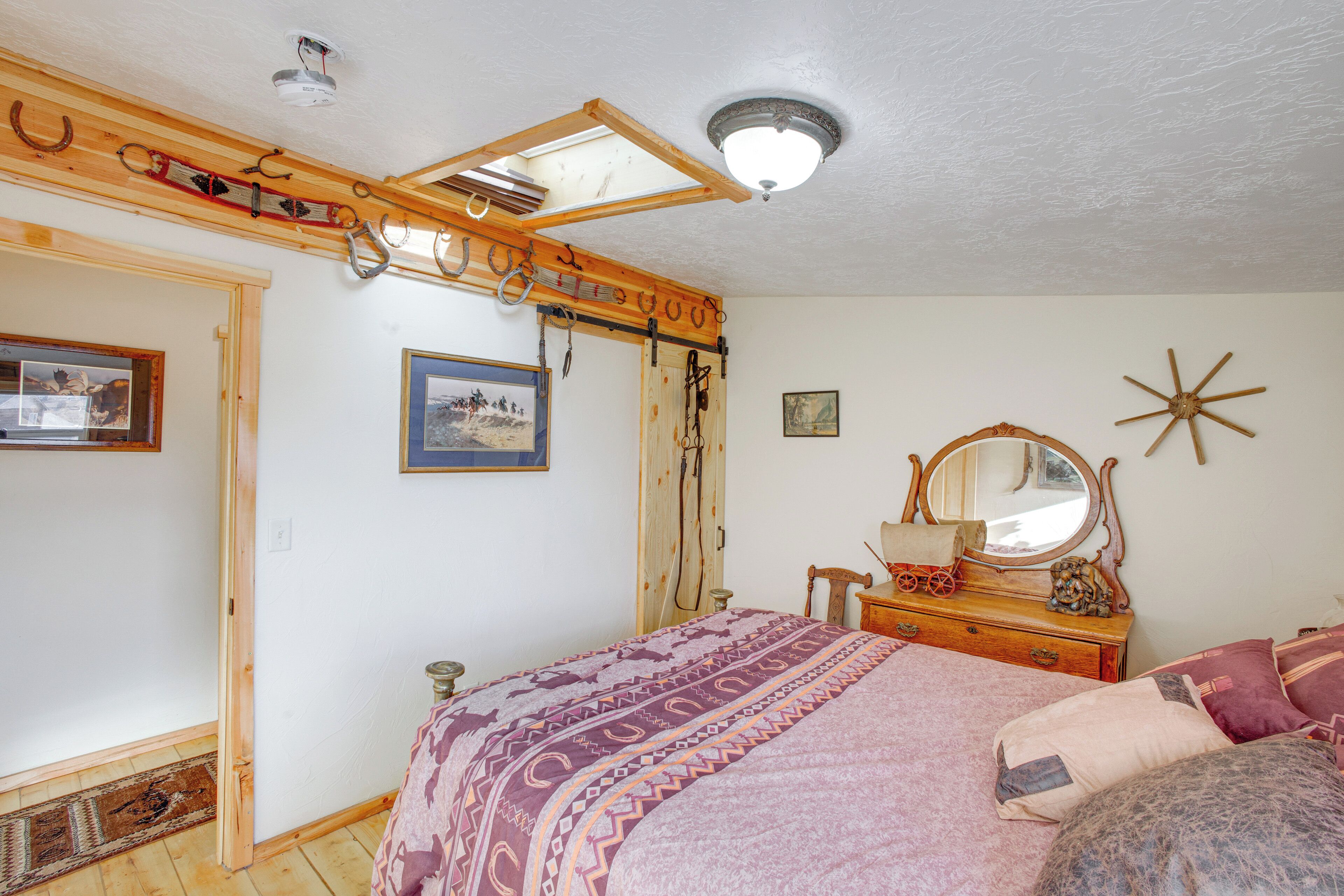 Un dormitorio con cama, cabecera de madera, cómoda, espejo y ventilador de techo.