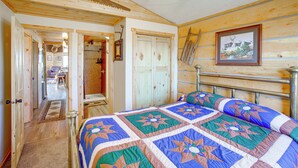 Un dormitorio de cabaña de madera con una cama, un ventilador de techo y un cuadro en la pared.