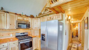 Una cocina de madera con un refrigerador, horno y microondas de acero inoxidable.