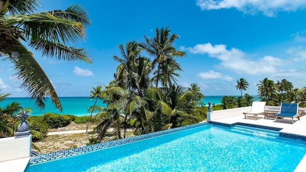 Une piscine d’un bleu éclatant, avec vue sur l’océan et les palmiers.