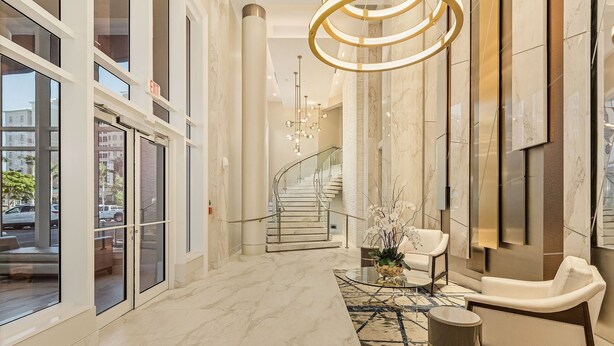 A spacious lobby with a marble floor, a staircase, and a seating area with a modern chandelier. - Grandview #603 - 4142 Bay Beach Ln 3 Bedroom Condo by RedAwning (Fort Myers Beach)