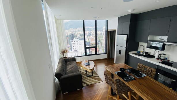 Un apartamento moderno con comedor, cocina y grandes ventanales con vistas a la ciudad.