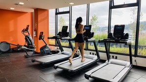 Un gimnasio con cintas de correr, elípticas y bicicletas estáticas.