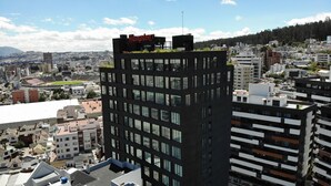 Un hotel moderno con jardín en la azotea, rodeado de edificios urbanos.