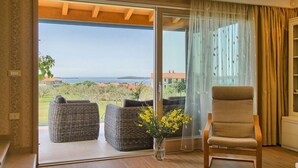 A balcony with wicker furniture, a chair, and a vase with yellow flowers. - Luxurious home in Fazana (Fazana)