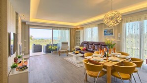 A spacious living room with a leather sofa, yellow chairs, a dining table set for four, and a large window offering a scenic view. - Luxurious home in Fazana (Fazana)