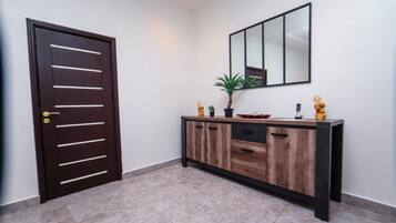 Un pasillo con una puerta de madera oscura, una consola con un espejo y una planta en maceta.