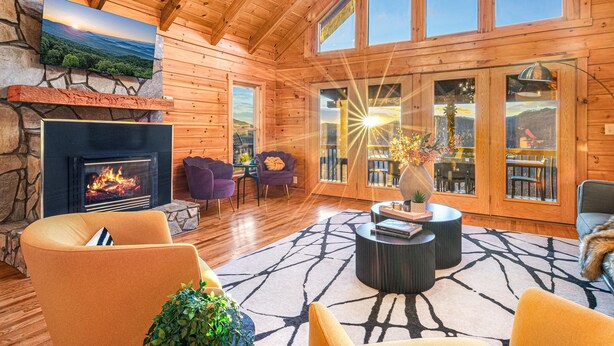 L’intérieur d’un chalet confortable, avec une cheminée, des sièges confortables, de grandes fenêtres et un mur en pierre.