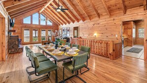 Une cabane en bois spacieuse, dotée d’un coin repas, de hauts plafonds et de grandes fenêtres.