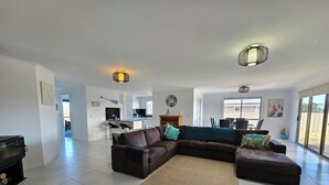 A spacious living room with a sectional sofa, a coffee table, and a large window providing a view of the backyard.