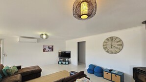 A modern living room with a sofa, coffee table, TV, and decorative items.