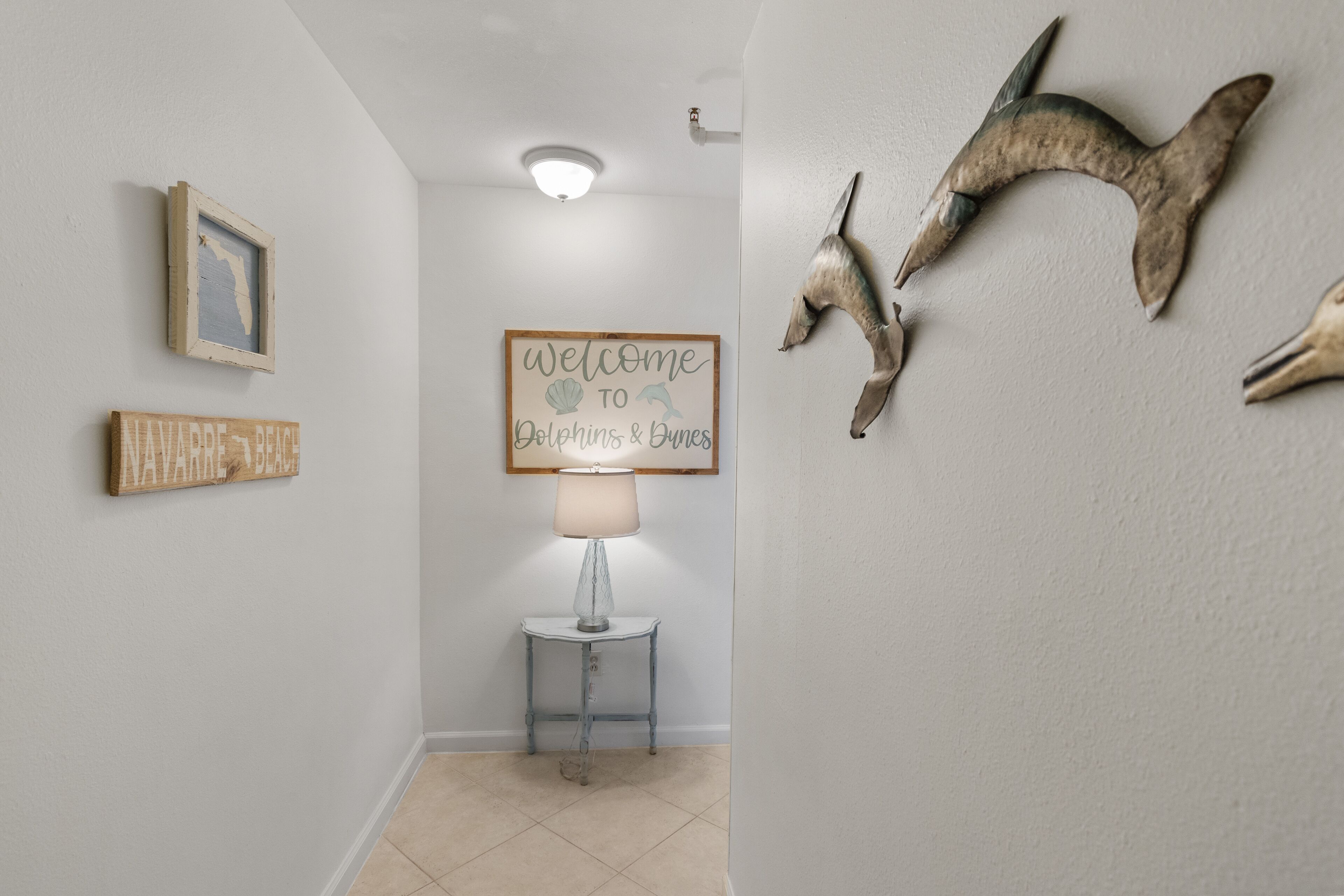 Een gang met een lijst met een kaart, een welkomstbord, een lamp en dierenhoorns aan de muur.