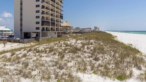 Et strandhotel med flere etager, en sandstrand foran og en mole i baggrunden.
