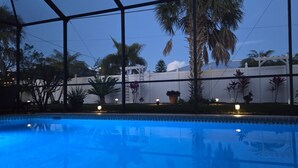Une piscine avec vue sur des palmiers et entourée d’une clôture blanche.