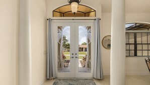 Un couloir avec une double porte donnant sur un patio extérieur.
