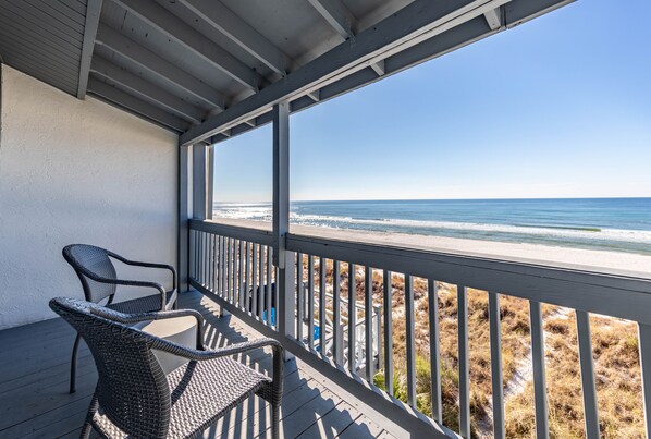 A covered outdoor area with wicker chairs and a view of the beach.