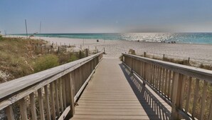 Une promenade en bois qui mène à une plage, avec un ciel dégagé.