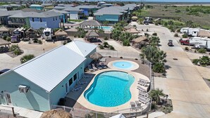A resort with a swimming pool, RV parking, and thatched-roof structures. - 8 Sailfish RV Resort, Port Aransas RV Getaway (Port Aransas)